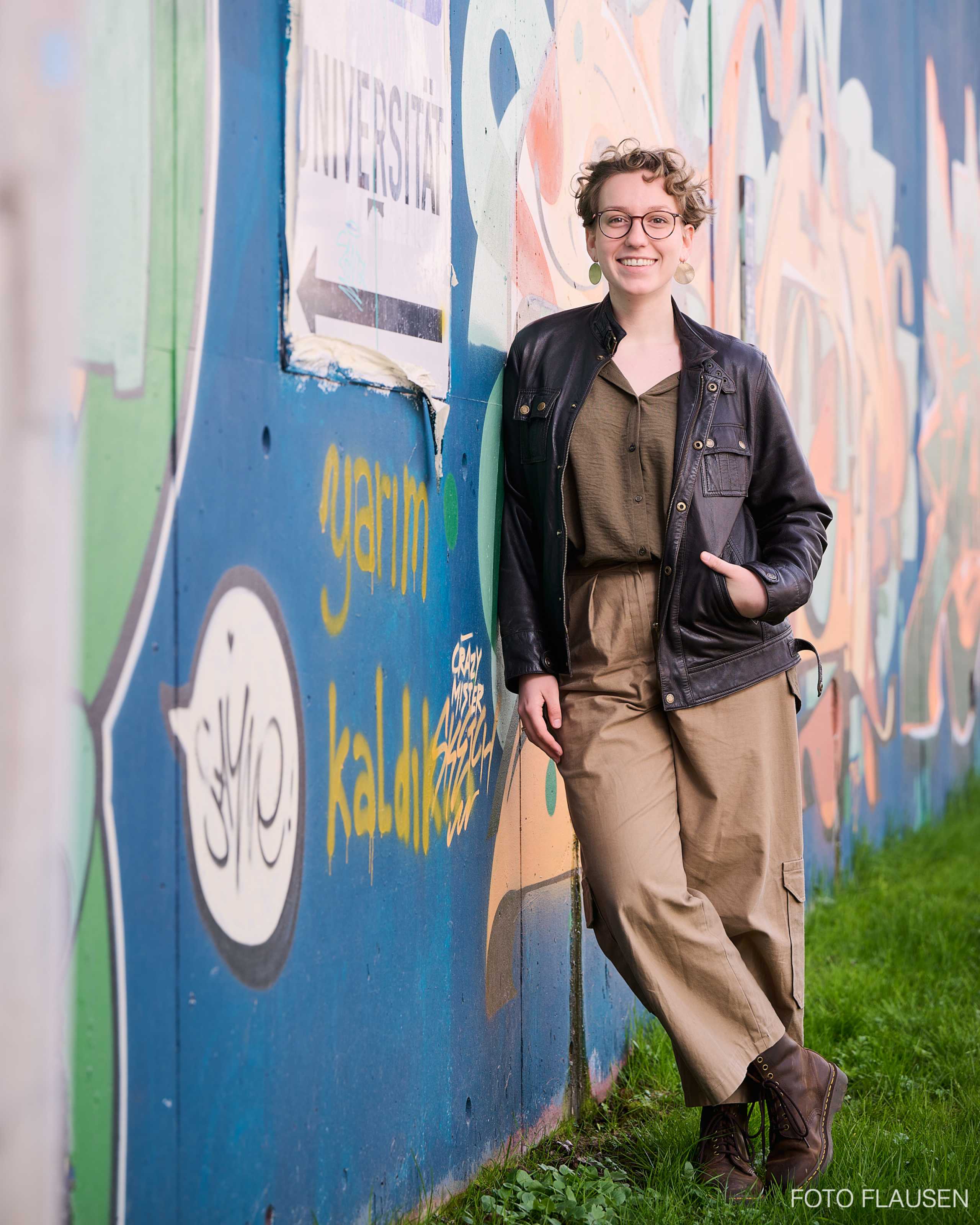 Hanna Pienz fotografiert vor einer Grafitti Wand in Salzburg für die Strassenzeiting Apropos