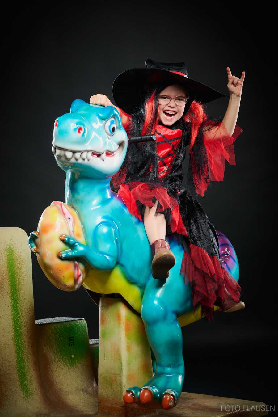 Fotoshooting im Fotostudio mit einer am Dinosaurier reitende Hexe